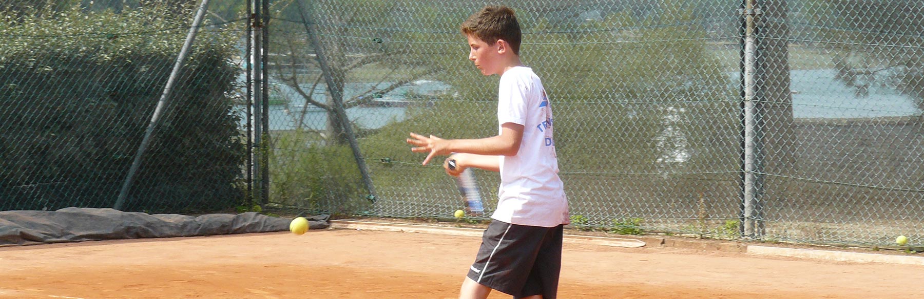 Un joueur de tennis junior exécute un coup droit.