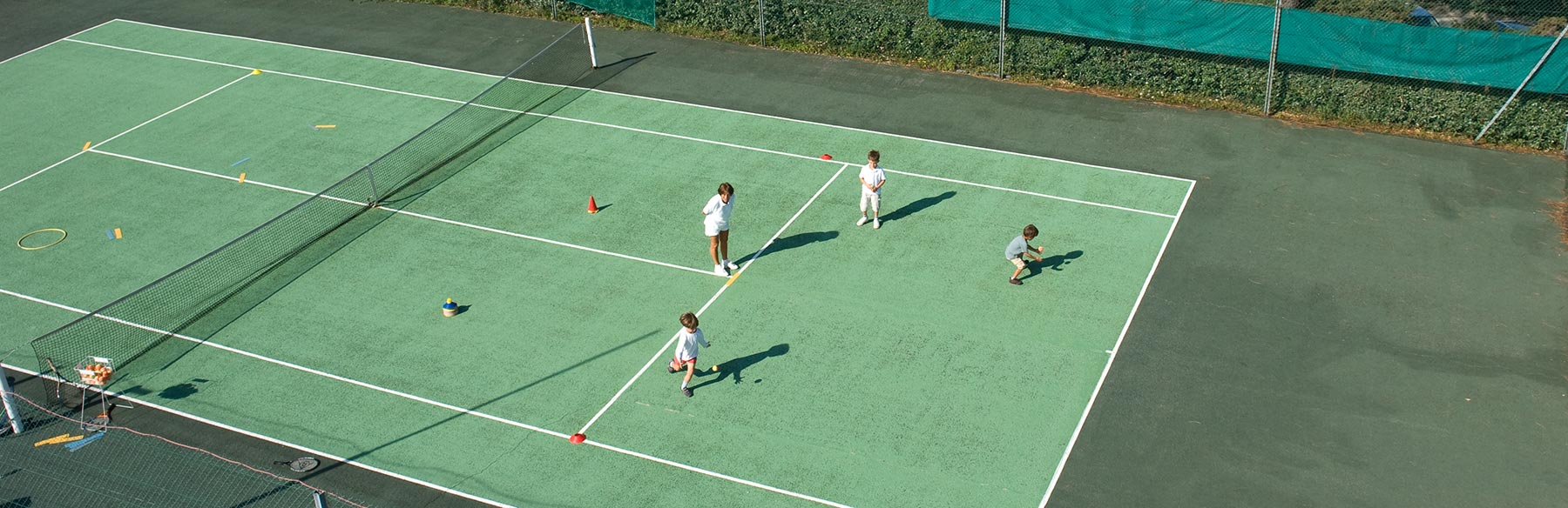 Une monitrice de tennis donne un cours à trois enfants.