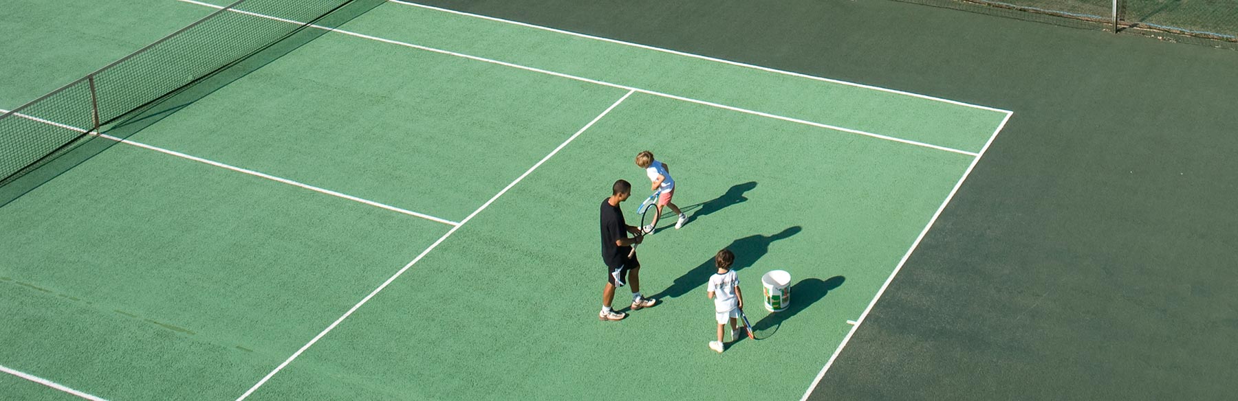 Un moniteur de tennis donne un cours à deux enfants.
